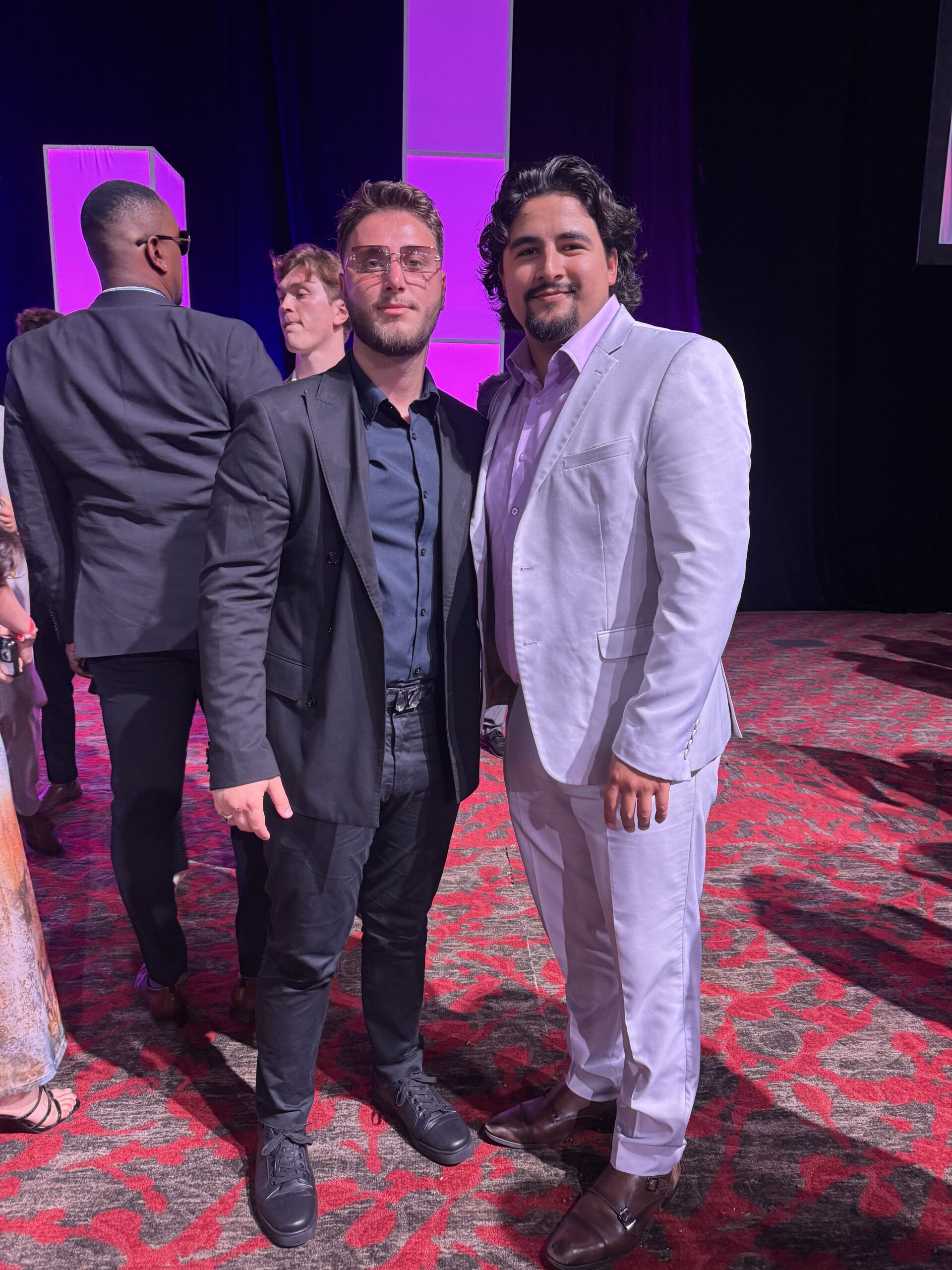 Two professional men in suits posing together on a red carpet at a corporate gala event.